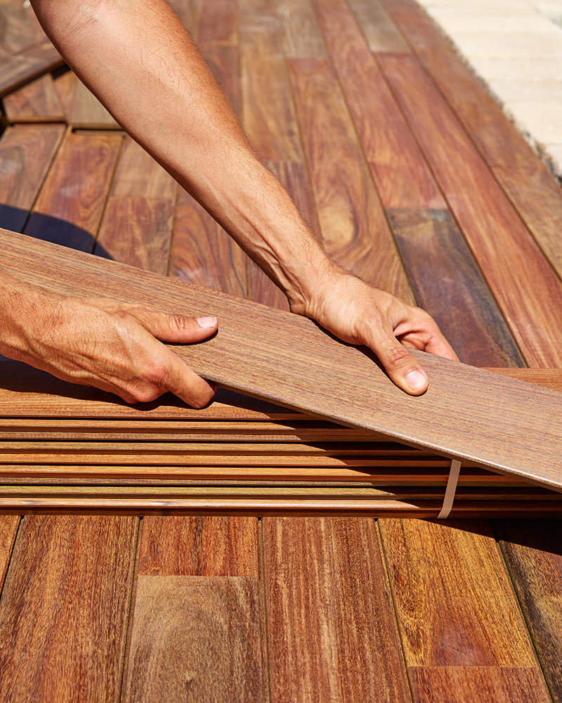 Ipe decking installation with carpenter hands holding tropical wood slats